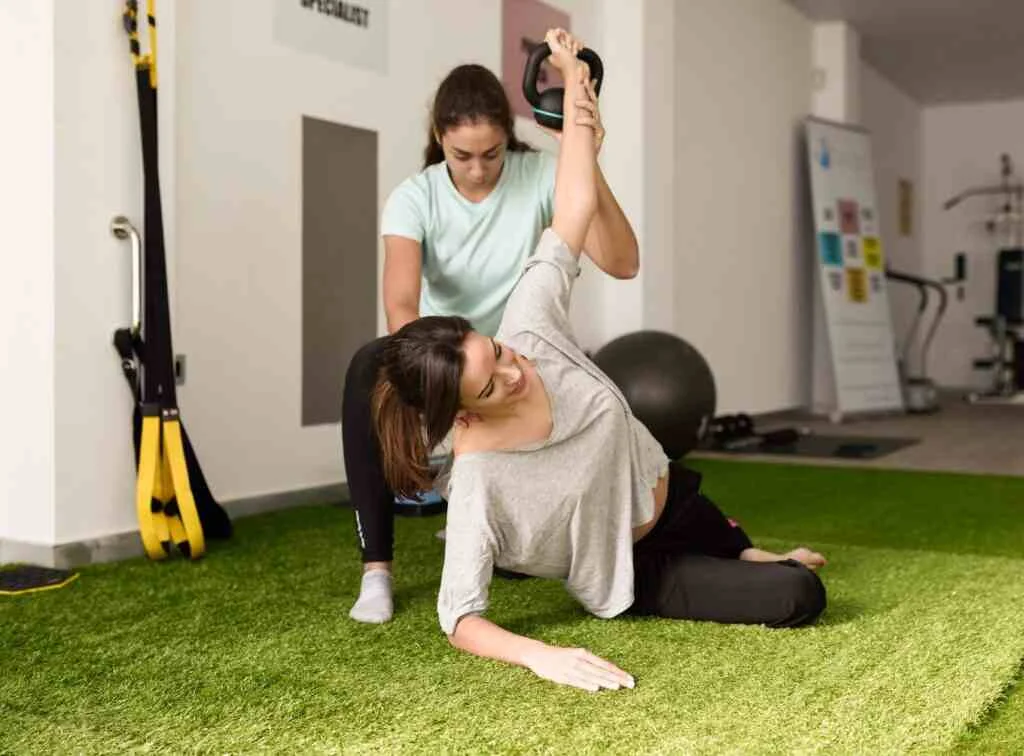 Physiotherapist assisting young caucasian woman with exercise wi